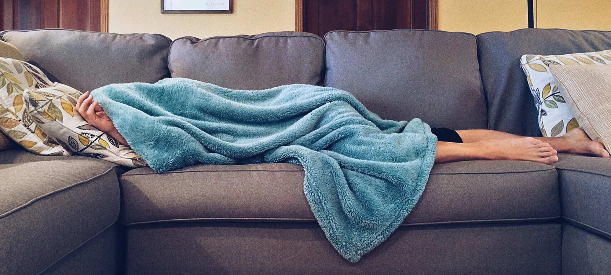 person lying down on a couch with a blanket on