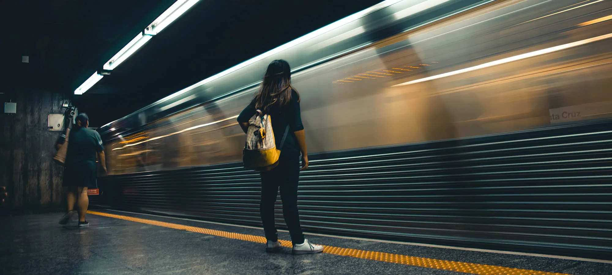 woman with bag standing on train platform