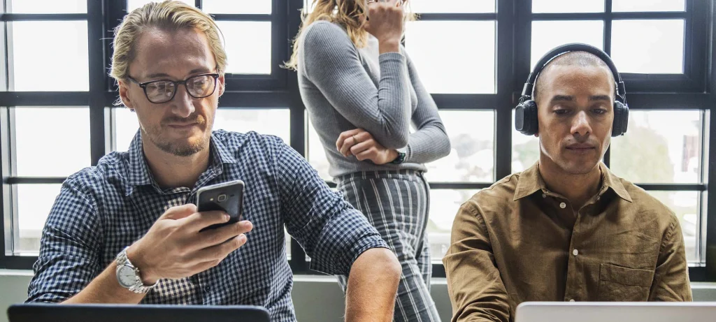 two office workers on their laptops and using their phones