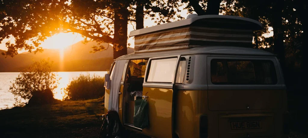 caravan parked in front of a lake at sunrise or sunset