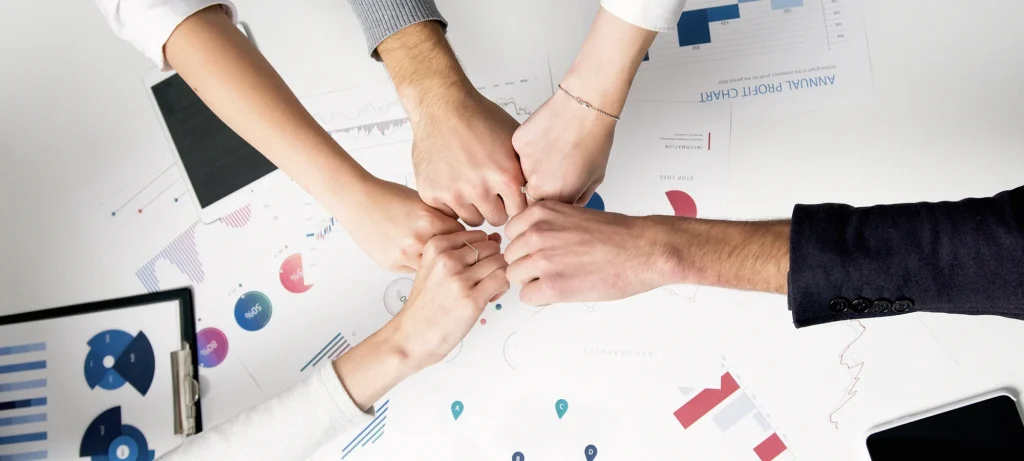 five employees holding their hands out and fist bumping