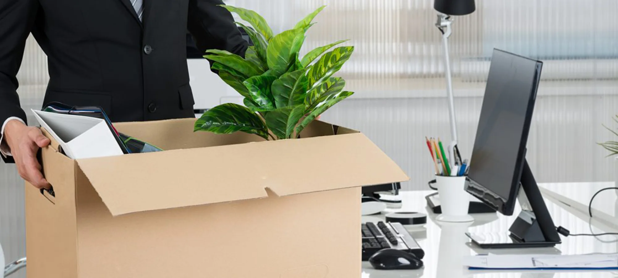 employee putting their office desk things into a cardboard box