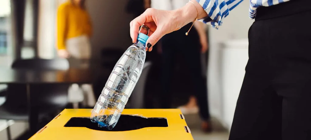 a person putting plastic bottle in the recycling bin