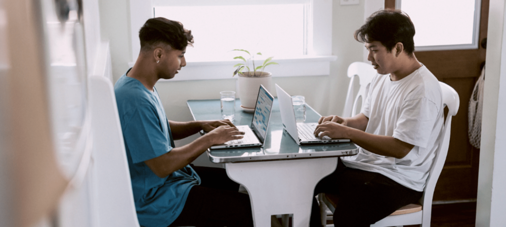 Two guys working on their laptops and discussing mental health